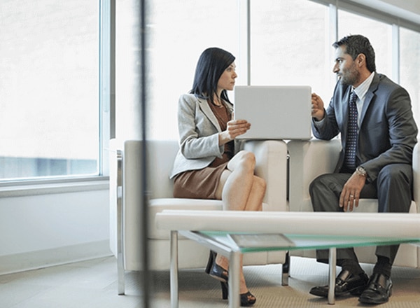 a woman and a man sitting in an office setting having a discussion
